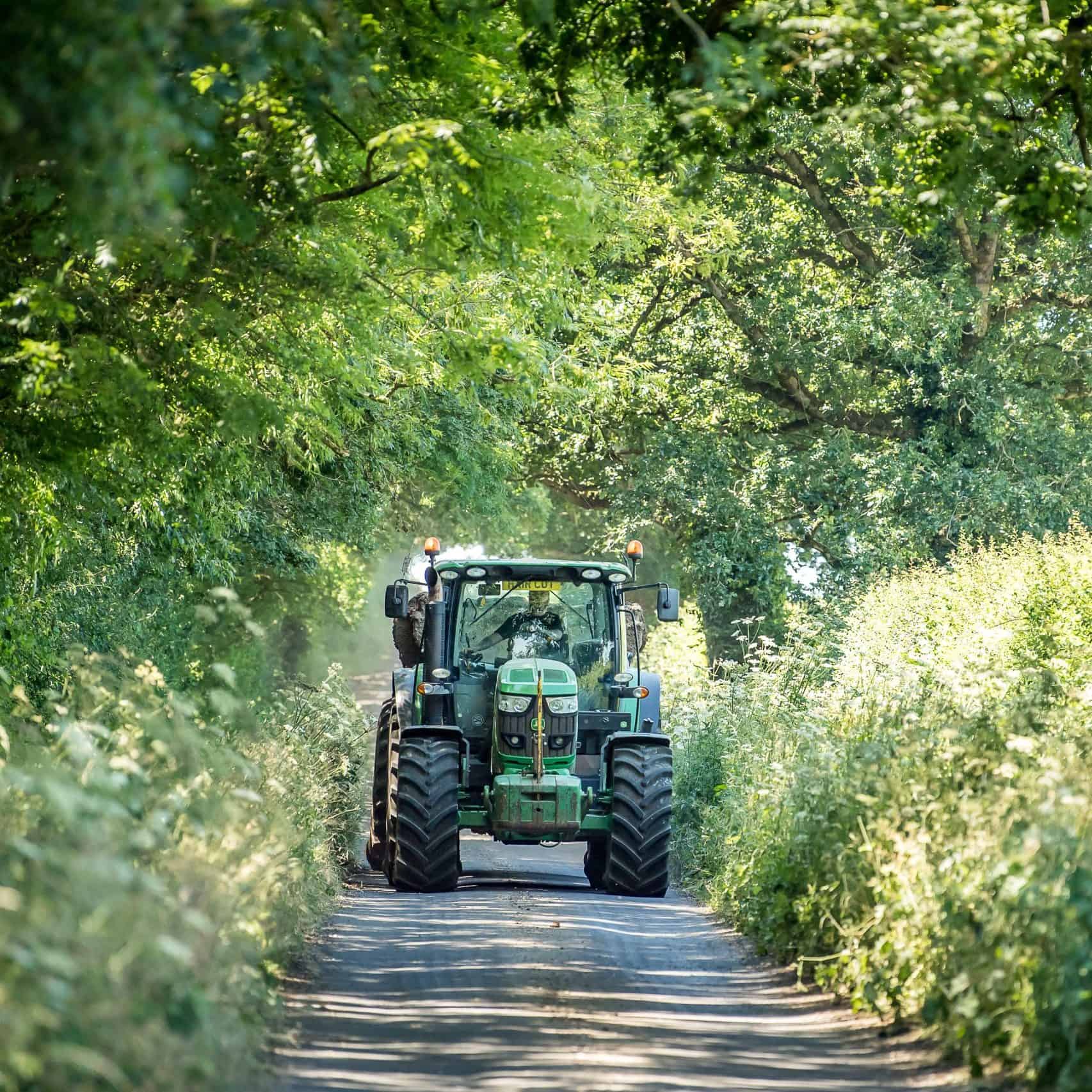 Tractor driving down country lane in summer